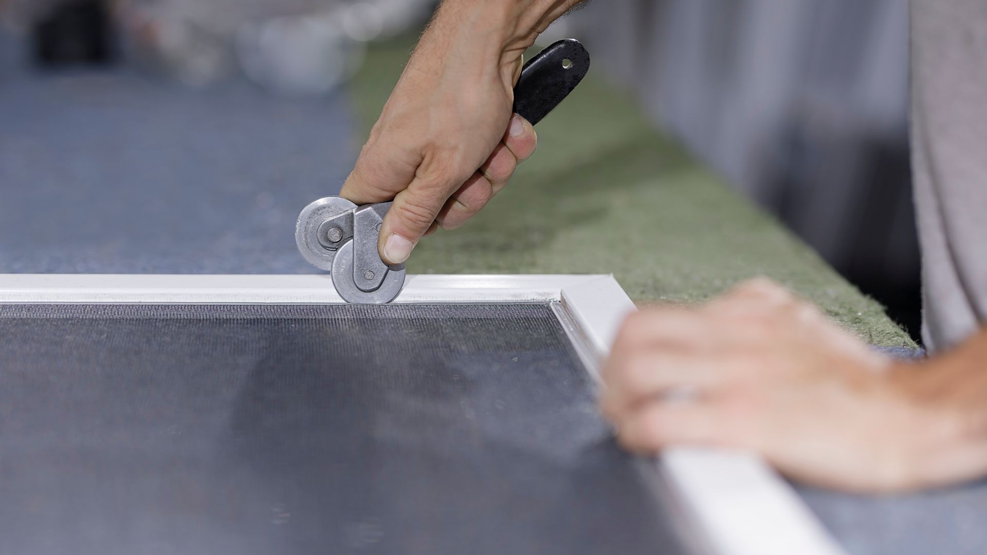 Hand using roller tool on edge of gray surface or material
