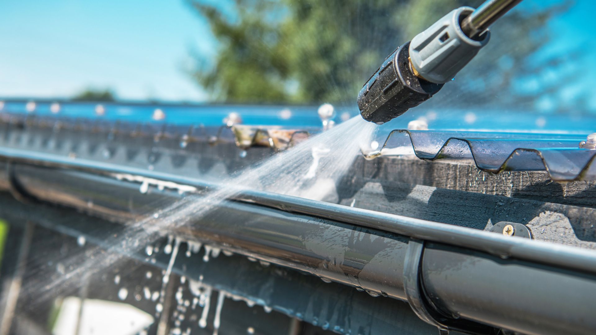Pressure washer cleaning a gutter with water spray