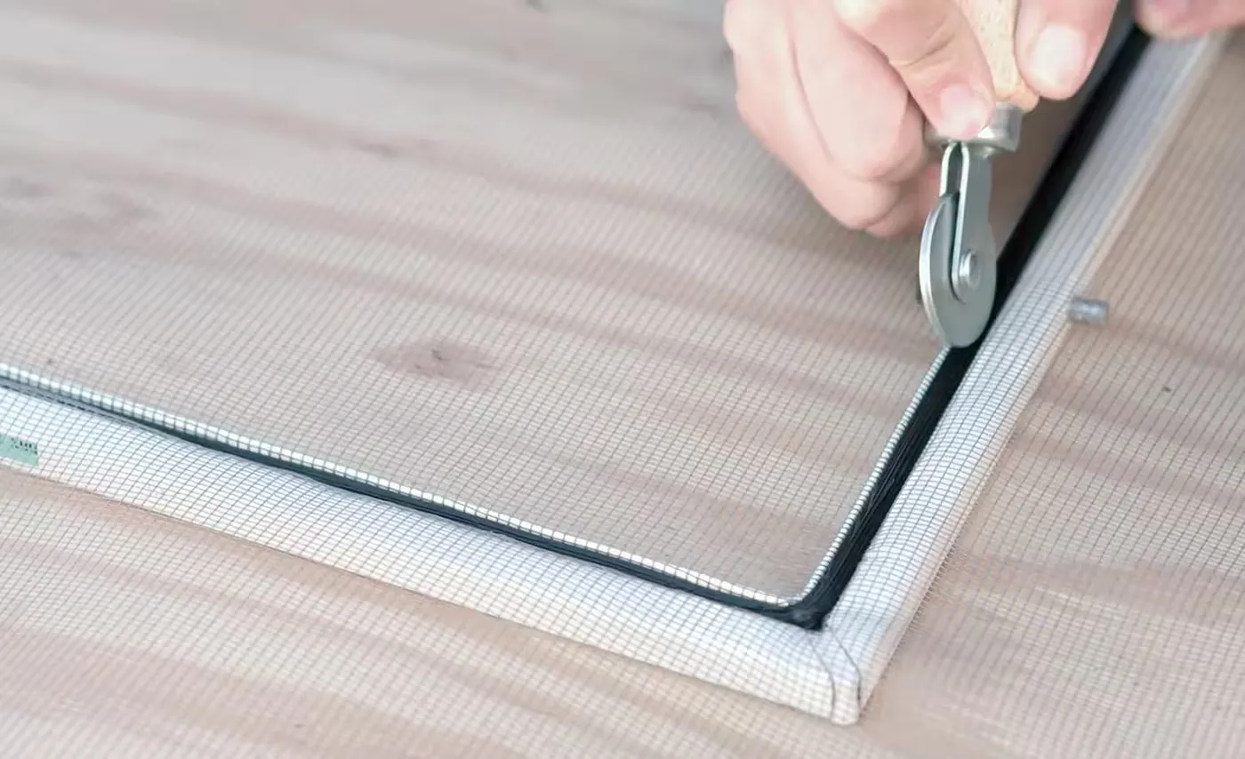 Re-screening a window screen with fresh mesh and spline during a screen repair