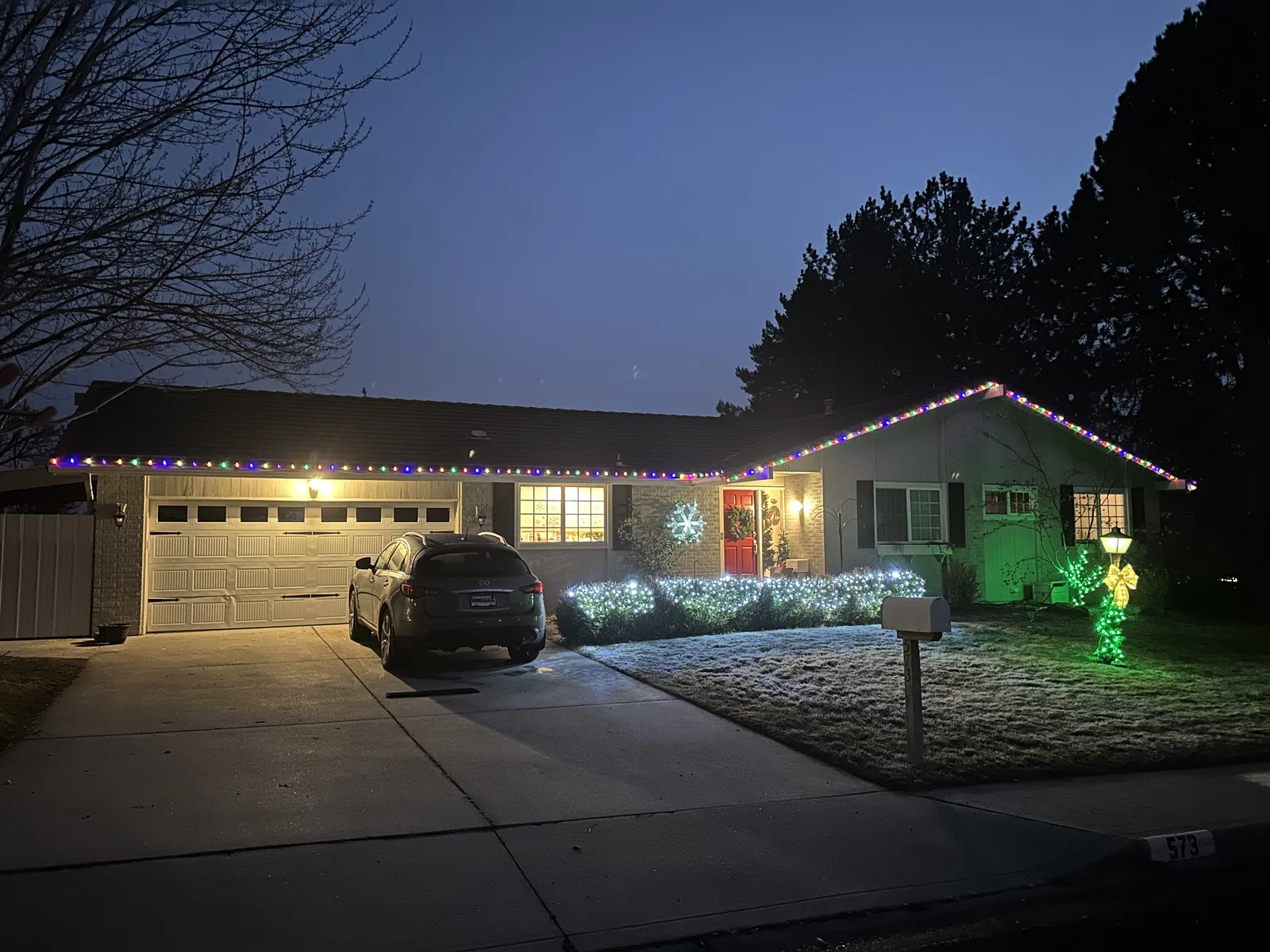 Boise home with custom Christmas lights along the roofline and lit decorations in the yard at dusk